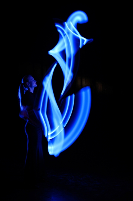 Jongleurin mit blau leuchtenden LED Keulen